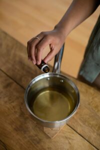 A person adding essential oil to candle wax for homemade aromatherapy candles.