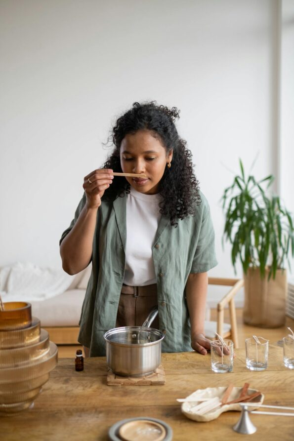 A woman engages in candle-making leisurely at a wooden table, enjoying a DIY hobby indoors.