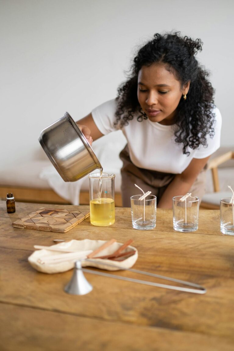 Black woman pouring hot wax for candle making, showcasing craft hobby indoors.
