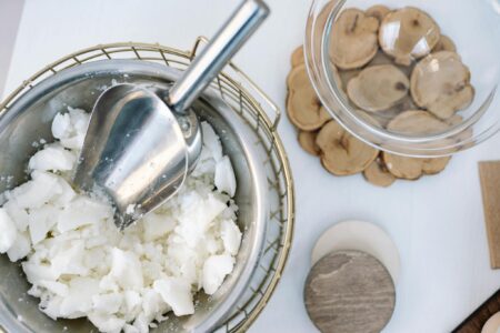 Flatlay of candle wax in a stainless steel bowl with a scooper, perfect for DIY projects.