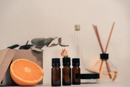 Elegant still life featuring aromatherapy bottles, orange slice, and dried flowers.